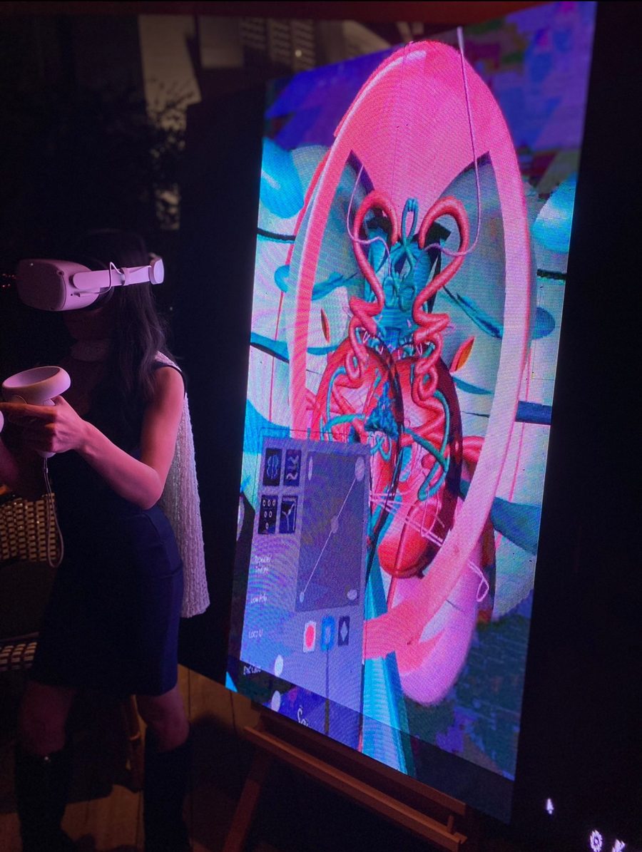Creatress sculpting in front of a large pink and blue screen