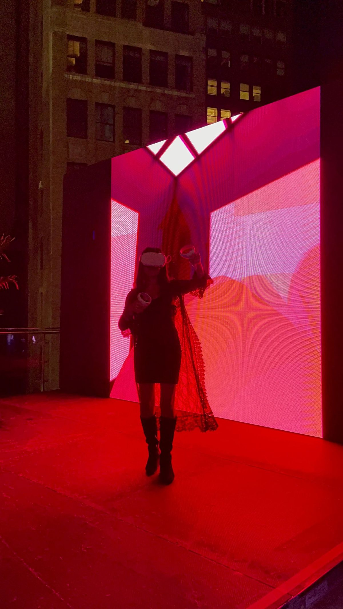 Creatress walking a red-lit stage in front of a glowing wall