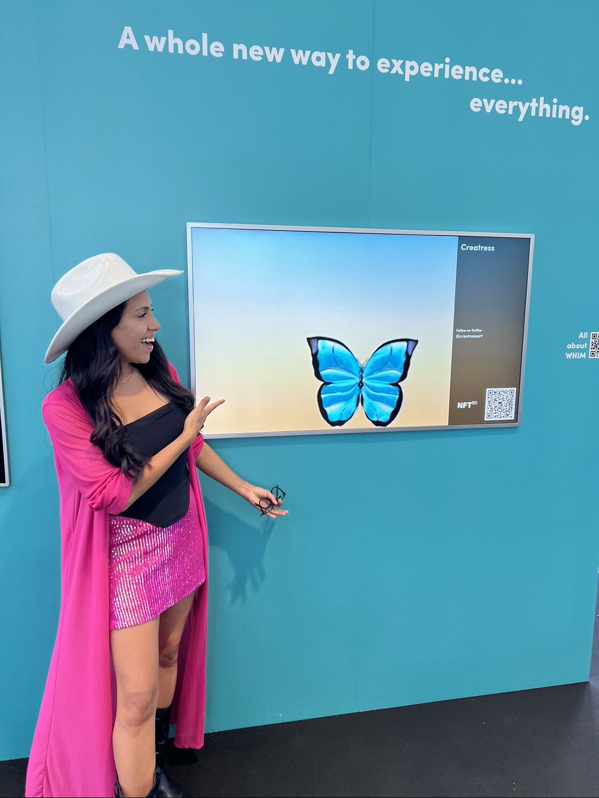 Creatress beside a screen showing a blue butterfly sculpture